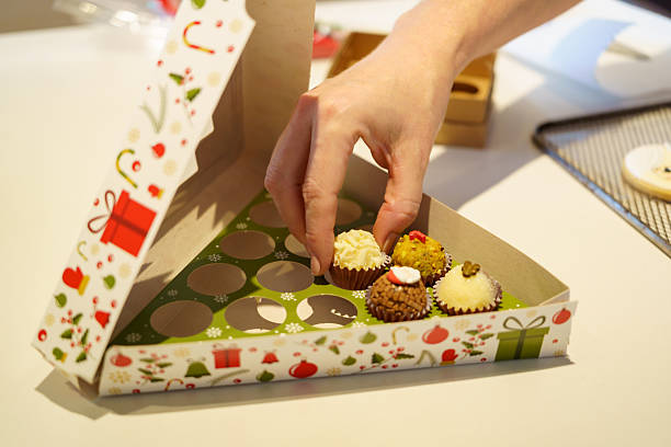 Hand placing brigadeiros into christmas holiday gift box