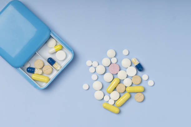 Pill box with pills on blue background. box container of tablets, vitamins for routine treatment.